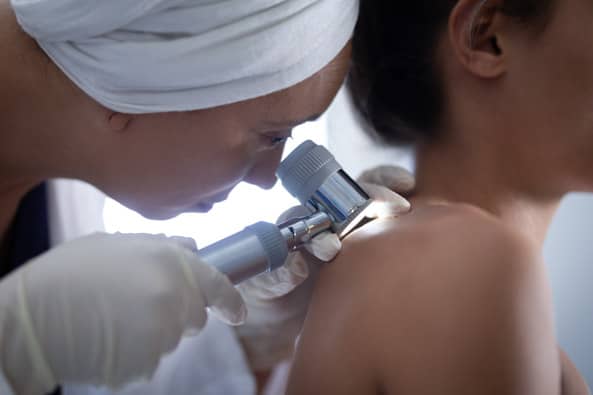Dermatóloga chequeando la piel de una mujer